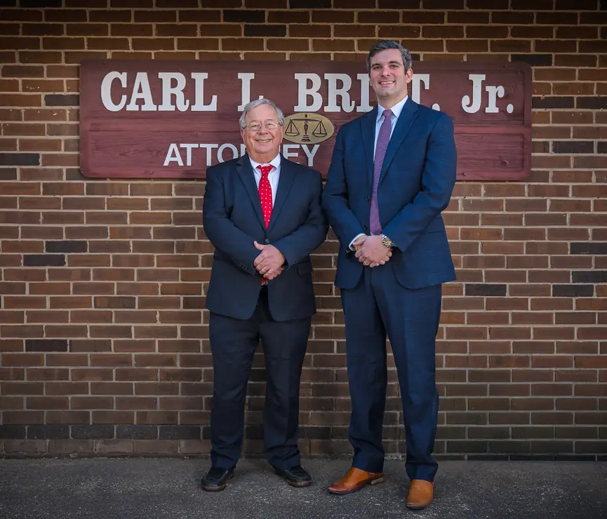 Carl L. Britt, Jr. and Zachary D. McLaurin in front of the firm's sign on its brick wall